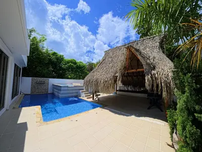 a resort with a thatch roof and a swimming pool at CountrySide Stay Melina in San Mateo