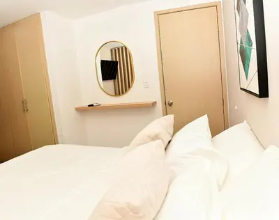 a bedroom with a white bed and a mirror at Apartamento familiar con excelente ubicación Barranquilla in Barranquilla