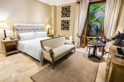 a bedroom with a bed and a chair and a television at Bastión Luxury Hotel in Cartagena de Indias