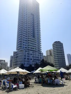 a group of people sitting under umbrellas on a beach at Apartamento 3404 Palmetto Beach Frente a la playa in Cartagena de Indias