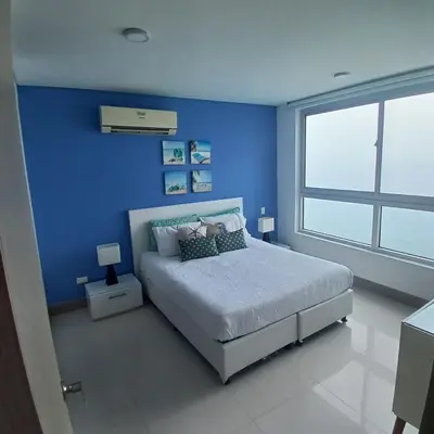 a blue bedroom with a bed and a large window at Apartamento 3404 Palmetto Beach Frente a la playa in Cartagena de Indias