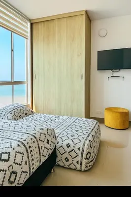 a bedroom with two beds and a flat screen tv at Lindo apto vista al mar,central y piscina rooftop in Cartagena de Indias