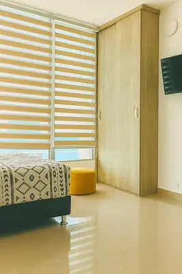 a bedroom with a bed and a window with blinds at Lindo apto vista al mar,central y piscina rooftop in Cartagena de Indias