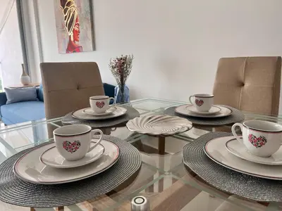 a glass table with three cups and plates on it at Confortable Apartamento Ocean Drive 711 -estancia mínima 2 noches- in Cartagena de Indias
