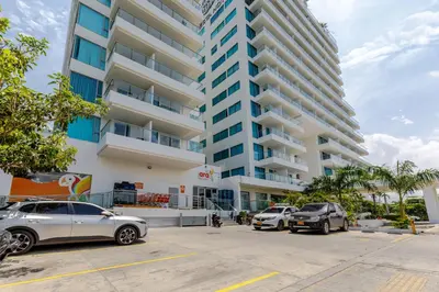 a parking lot with cars parked in front of a tall building at Espectacular apartamento en Cartagena Seaway935 - Morros in Cartagena de Indias