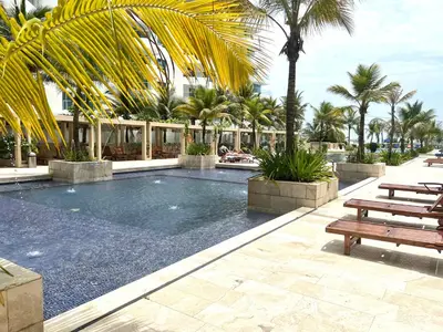 a swimming pool with two benches and palm trees at MORROS EPIC Un refugio frente al mar in Cartagena de Indias