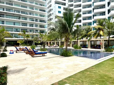 a resort pool with chairs and palm trees and a large building at MORROS EPIC Un refugio frente al mar in Cartagena de Indias