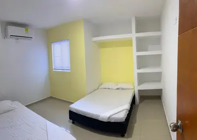 a small room with two beds and a shelf at Apartamento 202 in Cartagena de Indias