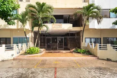 a building with palm trees in a parking lot at Apartamento Central Frente al Mar Cartagena in Cartagena de Indias