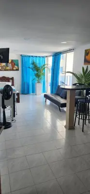 a living room with blue curtains and a table and chairs at Hermoso apartamento con vista al mar in Cartagena de Indias