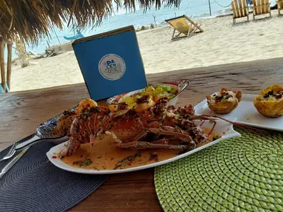 a lobster on a plate on a table next to a book at Palenque Beach House in San Onofre
