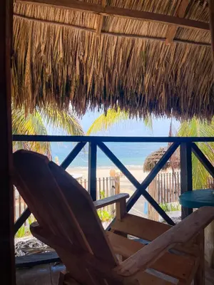 a chair under a straw umbrella on the beach at Palenque Beach House in San Onofre