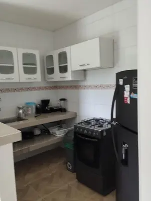 a kitchen with a black refrigerator and a stove at Apartahotel Eden Coveñas in Coveñas