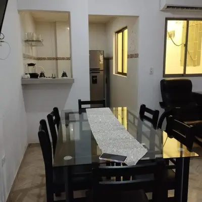 a glass table with black chairs and a kitchen at Apartahotel Eden Coveñas in Coveñas