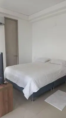 a white bedroom with a bed and a tv at Amazing views in Barranquilla in Barranquilla