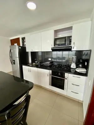 a kitchen with white cabinets and a stove and microwave at Apartment al-1 facing the sea with pool and Wifi in Cartagena de Indias