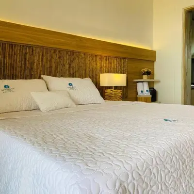 a large white bed in a bedroom with a lamp at Suite privada frente al mar, Tolú in San Silvestre
