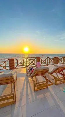 a person sitting on a deck watching the sunset at Suite privada frente al mar, Tolú in San Silvestre