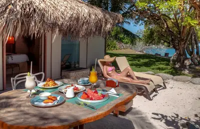 a woman sitting on a chair at a table with food on it at Hotel Rosario de Mar by Tequendama in Isla Grande