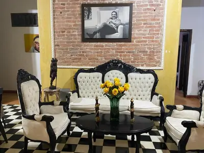 a living room with four chairs and a table with a vase of flowers at hotel san nicolas colonial in Barranquilla