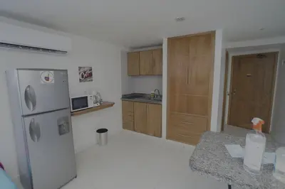 a kitchen with a white refrigerator and wooden cabinets at Apartamentos Bacanos in Cartagena de Indias