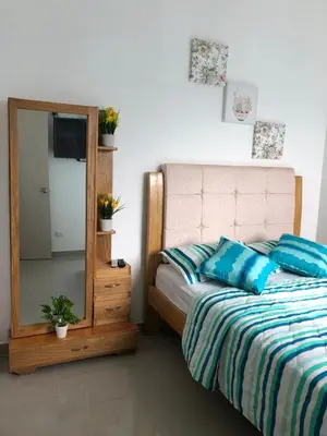 a bedroom with a bed with blue pillows and a mirror at Hermoso Apartamento en Caribe Campestre in Coveñas