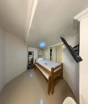 a small bedroom with a bed and a gun on the wall at Hostal Viva Mar in Cartagena de Indias