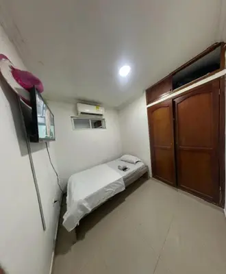 a small room with a bed and a wooden door at Hostal Viva Mar in Cartagena de Indias