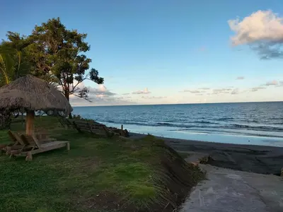 a picnic table and a straw umbrella on the beach at cabañas Brisas y Perla by AMAUNA in Moñitos