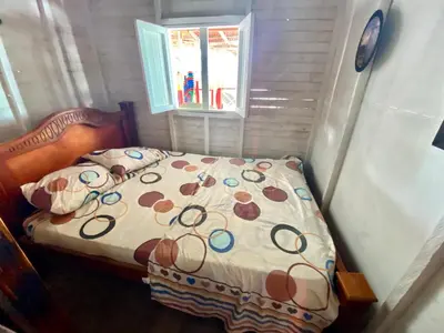 a small bedroom with a bed and a window at Hostal Paraiso in Isla Mucura