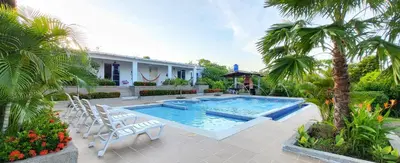 a swimming pool with chairs and a house at Extraordinaria Casa Finca Piscina AA in Sabanalarga