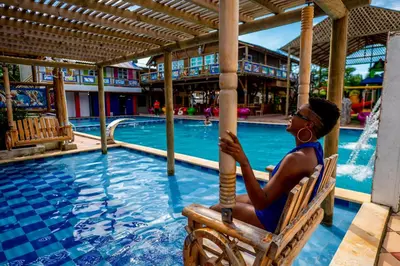 a woman sitting in a chair next to a swimming pool at Hotel Isla Lizamar in Isla Grande