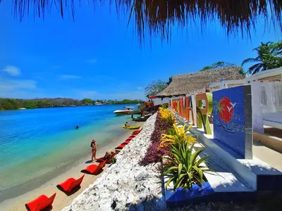 a beach with a group of red chairs and the ocean at Hotel Isla Lizamar in Isla Grande