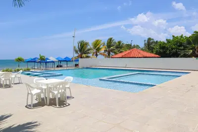 a swimming pool with tables and chairs next to the ocean at Mágico Apartamento Frente al Mar 3 Habitaciones PV82 in Coveñas