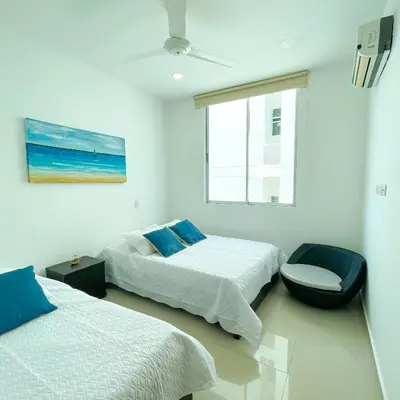 a bedroom with two beds and a chair and a window at Mágico Apartamento Frente al Mar 3 Habitaciones PV82 in Coveñas