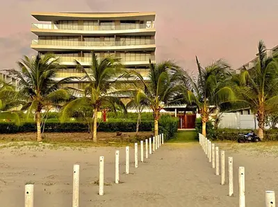 a beach with a fence and a building with palm trees at Morros Zoe - Beautiful Apartment on Manzanillo Beach in Cartagena de Indias