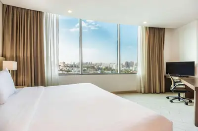 a hotel room with a bed and a desk and windows at Hilton Garden Inn Barranquilla in Barranquilla