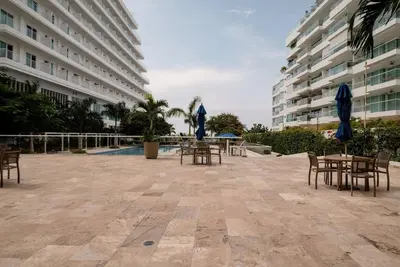 a patio with tables and chairs in front of a building at Moderno 3 hab con la mejor Vista en playa dormida Santa Marta in Santa Marta