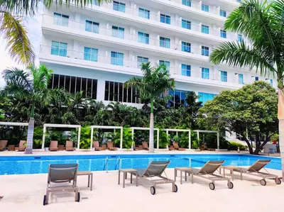 a hotel swimming pool with chairs and a building at Moderno 3 hab con la mejor Vista en playa dormida Santa Marta in Santa Marta