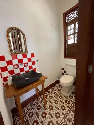 a bathroom with a toilet and a table with a mirror at Casa Blanca María Barranquilla - Authentic republican house in Barranquilla