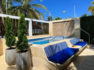 a swimming pool with two potted trees in front of it at Casa El Faro, Hermosa casa de playa in Cartagena de Indias