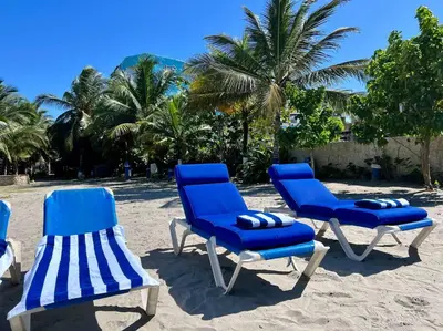 three blue beach chairs on a beach with palm trees at Casa El Faro, Hermosa casa de playa in Cartagena de Indias