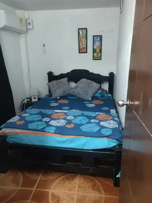 a bed with a blue comforter in a bedroom at Apartamento a unos pasos de la playa in Cartagena de Indias