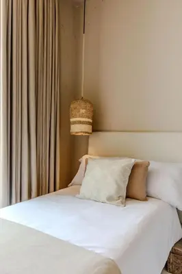 a bed with white sheets and pillows next to a window at Bondo Estudio in Cartagena de Indias