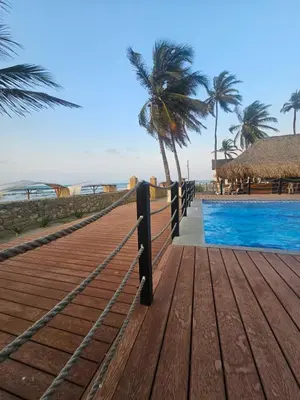 a wooden boardwalk next to a beach with a swimming pool at Apartamento 201 Palmar de los vientos in San Bernardo del Viento