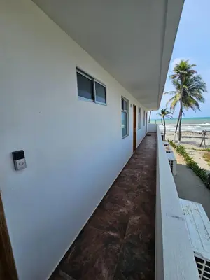 a white building with a bench next to the beach at Apartamento 201 Palmar de los vientos in San Bernardo del Viento