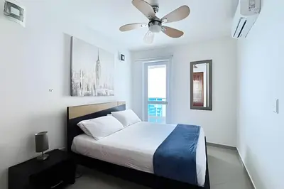 a white bedroom with a bed and a ceiling fan at Apartamento 2 Dormitorios Laguito. Vista Mar in Cartagena de Indias