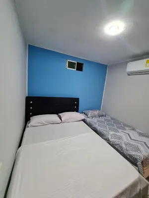 a bed in a small room with a blue wall at Apartamentos La Marina in Cartagena de Indias