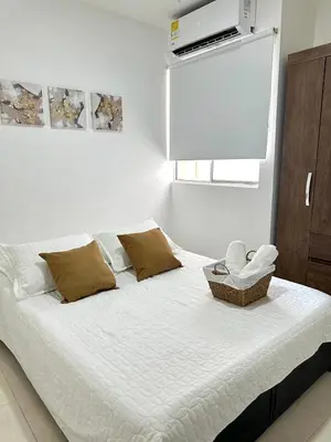 a bedroom with a bed with white sheets and a window at Apartamento vacacional cerca del mar in Cartagena de Indias