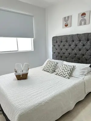 a bedroom with a large white bed with a headboard at Apartamento vacacional cerca del mar in Cartagena de Indias